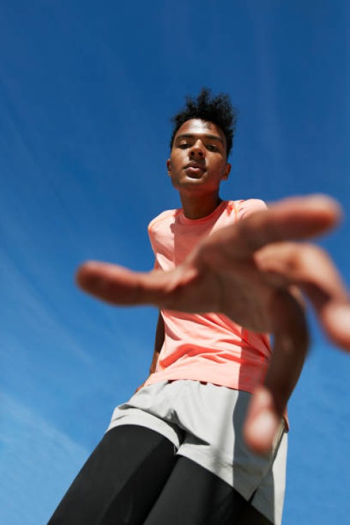 portrait of male athlete gesturing against blue sky - fashion stock-fotos und bilder