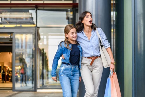 portrait of mother and daughter standing near the shopping window and browsing the store. - fashion stock pictures, royalty-free photos & images