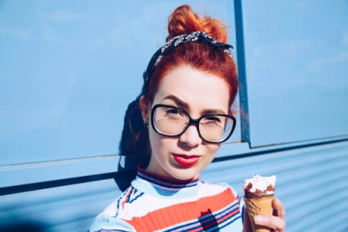 portrait of redhead young woman holding ice cream cone against mini van - fashion stock pictures, royalty-free photos & images