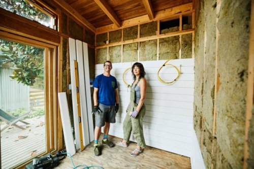portrait of smiling couple standing in room being remodeled during home improvement project - home decoration stock pictures, royalty-free photos & images