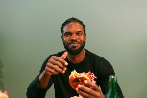 portrait of smiling man eating burger at restaurant - junk food stock pictures, royalty-free photos & images