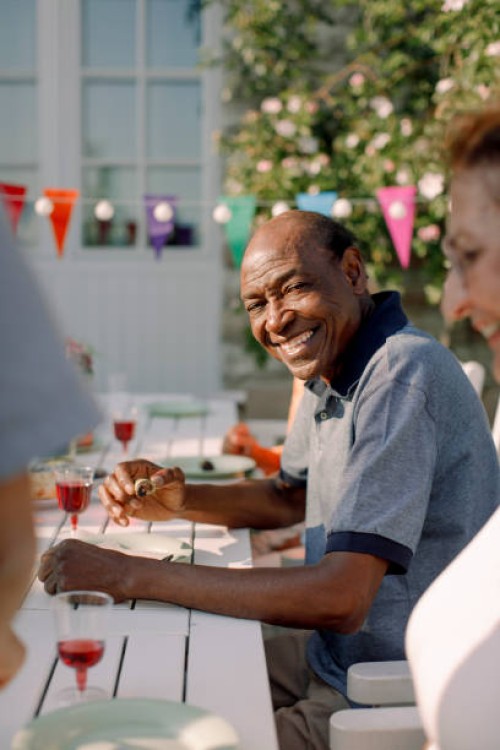 portrait of smiling senior man sitting with woman at dining table in back yard - garden decoration photos et images de collection