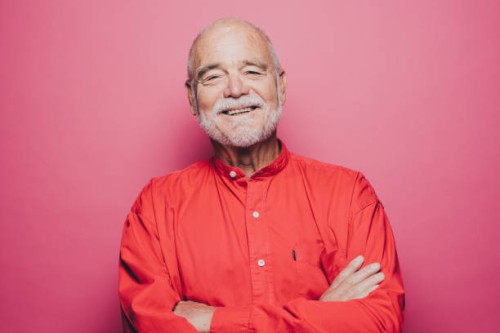portrait of smiling senior man with arms crossed against pink background - fashion stock pictures, royalty-free photos & images