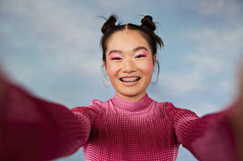 portrait of smiling teenage girl with pigtails taking selfie against colored background - fashion fotografías e imágenes de stock