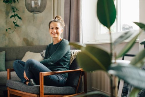 portrait of smiling woman sitting on armchair at home - home decoration stock pictures, royalty-free photos & images
