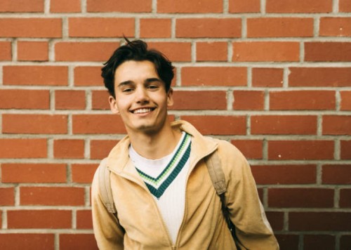 portrait of smiling young man against brick wall - fashion stock pictures, royalty-free photos & images