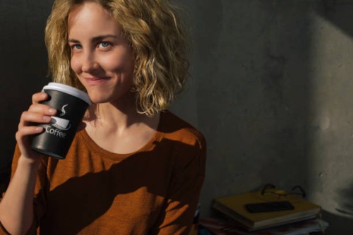 portrait of smiling young woman drinking coffee to go at home - junk food stock pictures, royalty-free photos & images