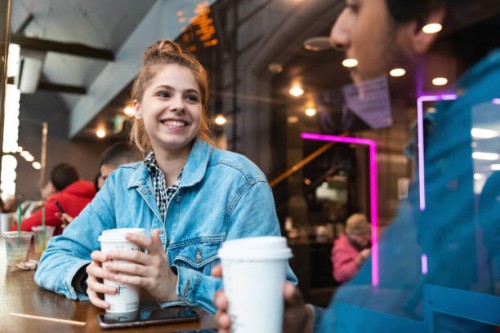 portrait of smiling young woman in a coffee shop looking at young man - junk food stock pictures, royalty-free photos & images