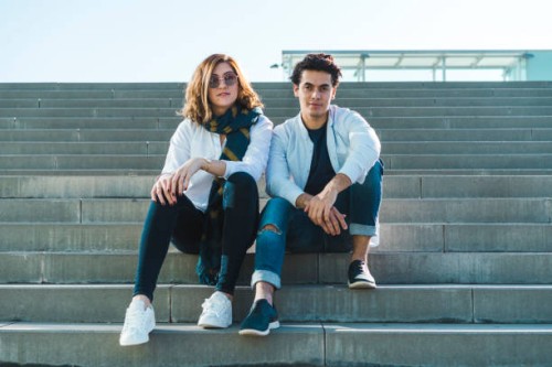 portrait of stylish young couple sitting on stairs outdoors - fashion stock pictures, royalty-free photos & images