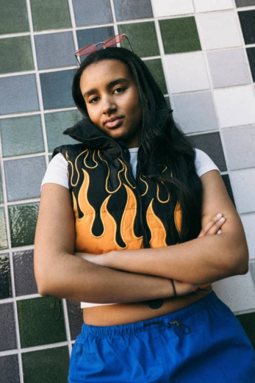 portrait of teenage girl standing with arms crossed against tiled wall - fashion stock pictures, royalty-free photos & images
