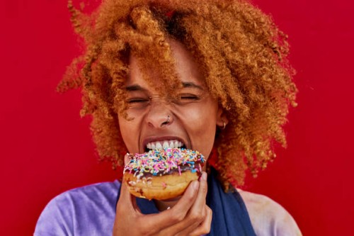 portrait of woman eating a donut - food stock pictures, royalty-free photos & images