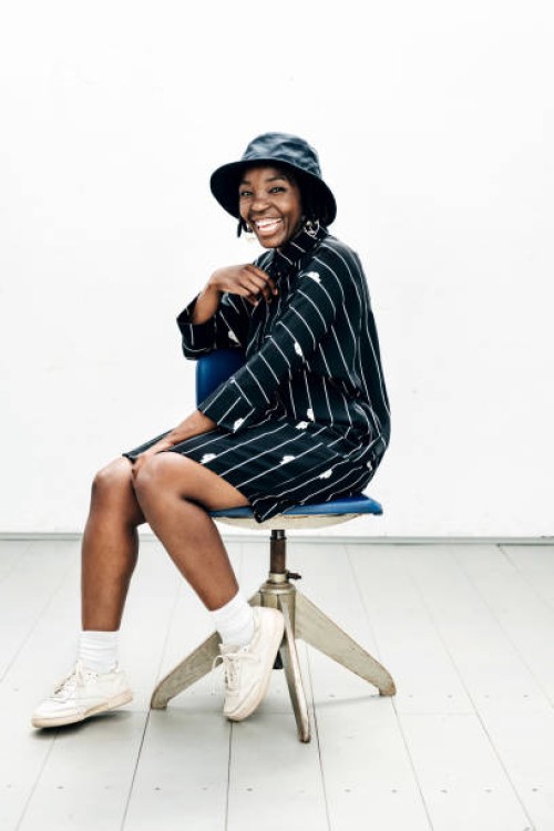 portrait of woman in striped dress sitting on stool - fashion stock pictures, royalty-free photos & images