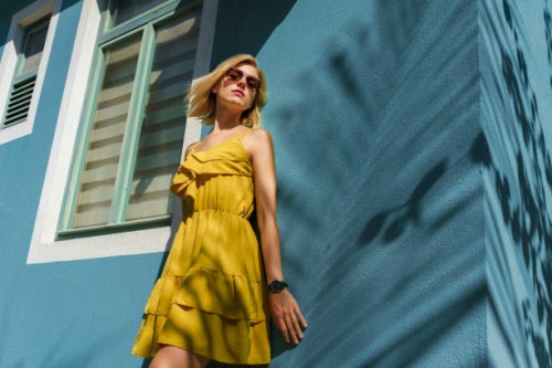portrait of woman smiling against wall with palm tree shade - fashion stock pictures, royalty-free photos & images