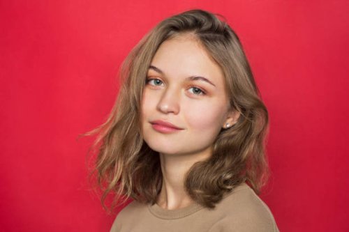 portrait of woman with light brown hair and smiling against red background - hairstyle stock pictures, royalty-free photos & images