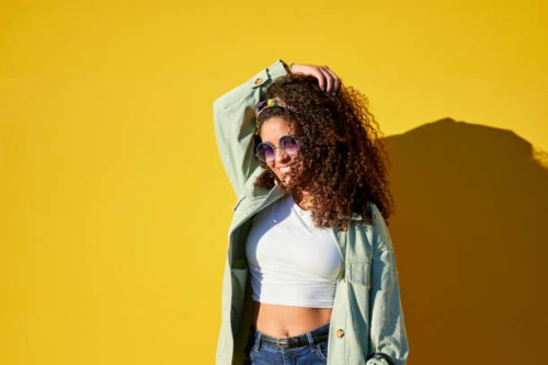 portrait of woman with sunglasses touching her afro hair on yellow background - fashion stock pictures, royalty-free photos & images