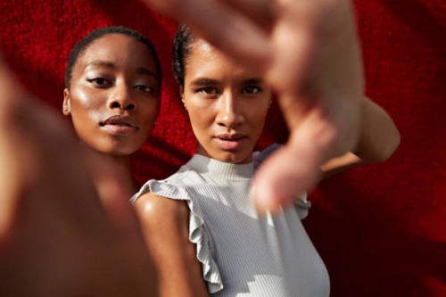 portrait of women gesturing against red wall - fashion stock pictures, royalty-free photos & images