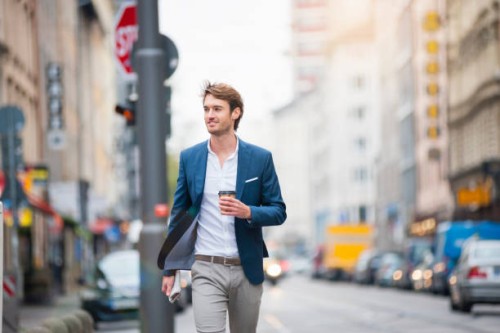 portrait of young businessman with newspaper and coffee to go walking on the street - junk food stock pictures, royalty-free photos & images