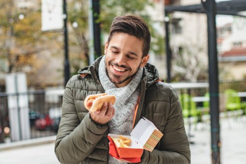 portrait of young man eating fast food - junk food stock pictures, royalty-free photos & images