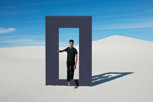 portrait of young man walking through door frame at desert - fashion stock pictures, royalty-free photos & images