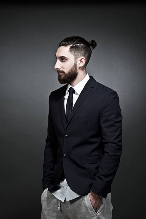 portrait of young man wearing black jacket and jogging pants in front of grey background - hairstyle stock pictures, royalty-free photos & images