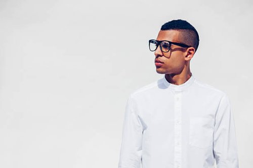 portrait of young man with shaved hair and glasses wearing white shirt in front of white background - hairstyle stock pictures, royalty-free photos & images