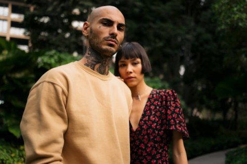 portrait of young serious couple standing in the park - fashion stockfoto's en -beelden