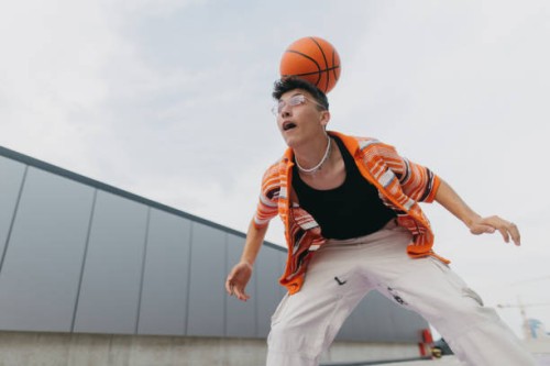portrait of young stylish generation z boy doing basketball tricks outdoors. - fashion stock pictures, royalty-free photos & images