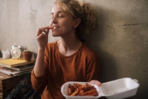 portrait of young woman eating french fries at home - junk food stock pictures, royalty-free photos & images