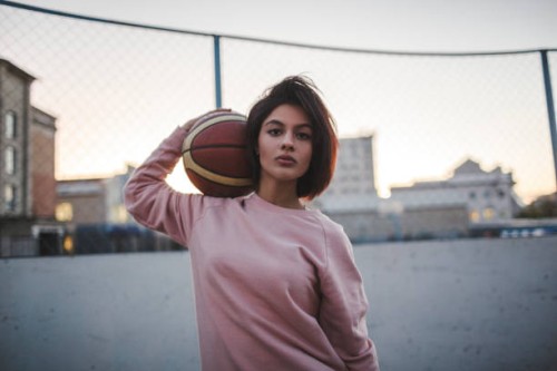 portrait of young woman holding basketball outdoors - fashion stock-fotos und bilder