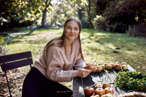 portrait of young woman sitting at table in garden - garden decoration stock pictures, royalty-free photos & images