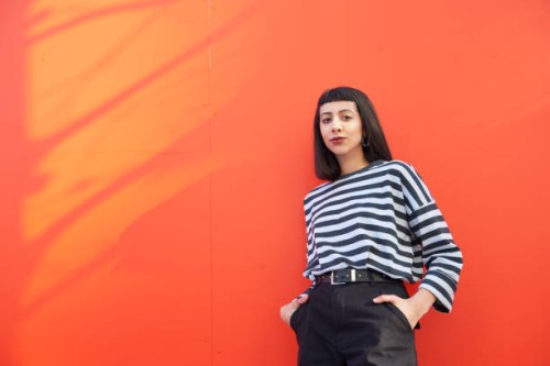 portrait of young woman standing against red background. - fashion stock pictures, royalty-free photos & images