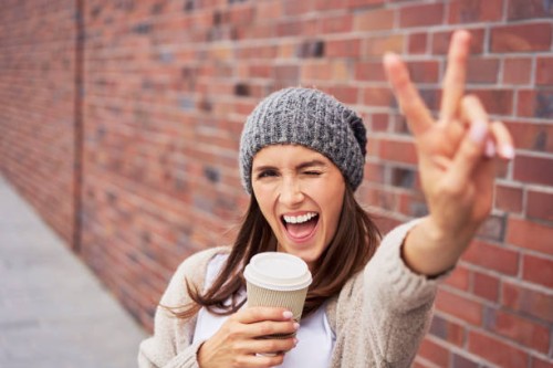portrait of young woman with coffee to go showing victory sign - junk food stock pictures, royalty-free photos & images