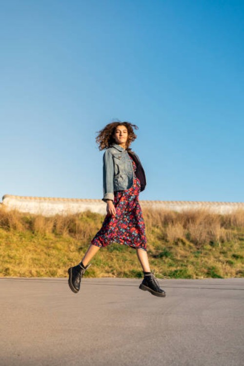 portrait of young woman with curly brown hair jumping in the air - fashion stock pictures, royalty-free photos & images