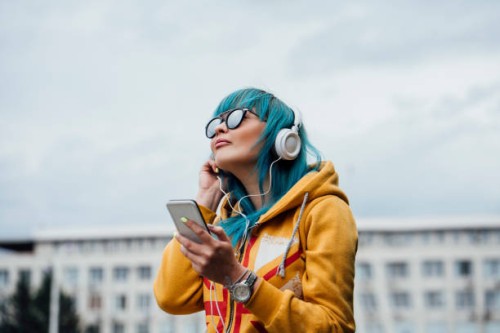portrait of young woman with dyed blue hair listening music with smartphone and headphones - fashion stock pictures, royalty-free photos & images
