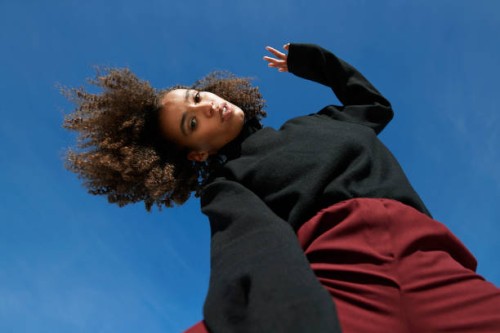portrait of young woman with head cocked against blue sky - fashion stock pictures, royalty-free photos & images