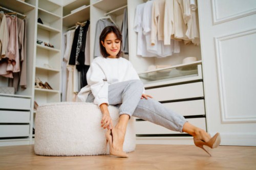 posh brunette woman putting high heels shoes on soft stool in the closet of the store - fashion stock pictures, royalty-free photos & images