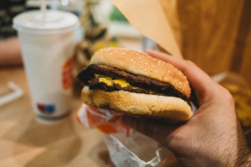 pov view of a man holding a cheeseburger - junk food stock pictures, royalty-free photos & images