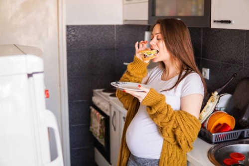 pregnant woman eating a sandwich at home - food stock pictures, royalty-free photos & images