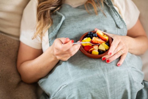 pregnant woman eating fruit salad, midsection - food stock pictures, royalty-free photos & images