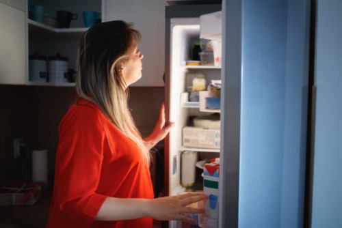 pregnant woman in front of the open fridge in the middle of the night - junk food stock pictures, royalty-free photos & images
