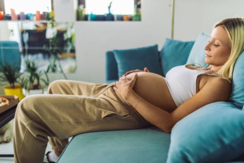 pregnant woman touching her abdomen at home - junk food stock pictures, royalty-free photos & images