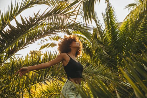 pretty young afro woman among palm trees - travel stockfoto's en -beelden