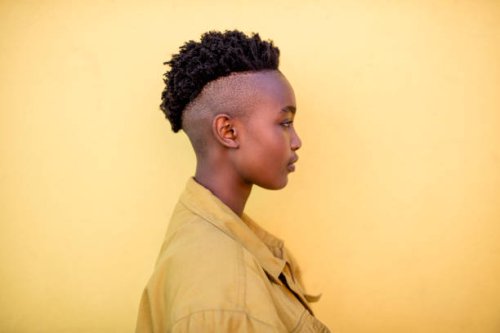 profile of a serious young woman wearing yellow jacket in front of yellow wall - hairstyle stock pictures, royalty-free photos & images