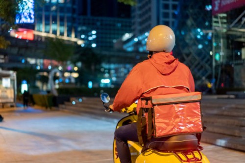 rear-view of delivery person driving scooter through city in the night - food stock pictures, royalty-free photos & images