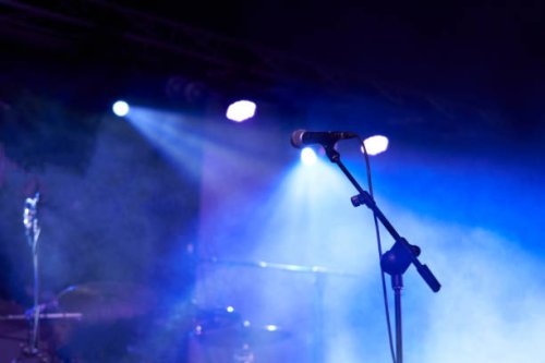 rear view low angle view of a microphone and spotlights on stage at a live concert with musical instruments background - concert stock pictures, royalty-free photos & images
