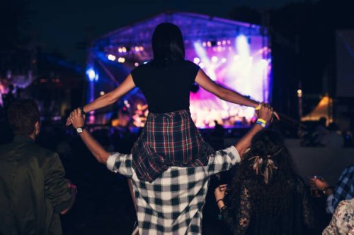 rear view of a girl getting carried on a friends shoulders at the music festival. - concert stock pictures, royalty-free photos & images