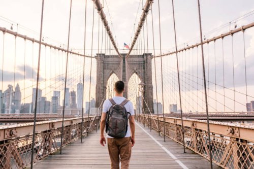 rear view of a young man with backpack walking on brooklyn bridge, new york city, usa - travel photos et images de collection