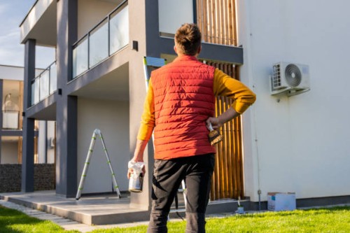 rear view of man with paintbrush and paintcan looking at apartment from yard - home decoration stock pictures, royalty-free photos & images