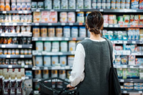 rear view of young asian mother with a shopping cart grocery shopping for baby products in a supermarket. she is standing in front of the baby product aisle and have no idea which product to choose from - food stock pictures,