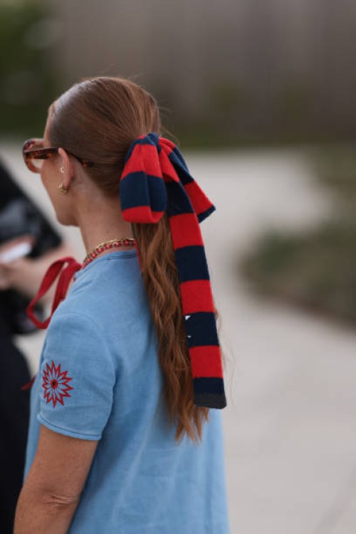 Rebecca Ferraz-Wyatt is seen wearing a blue and red striped bow in her hair; oversize round sunglasses with Havana frame and orange gradient lenses...